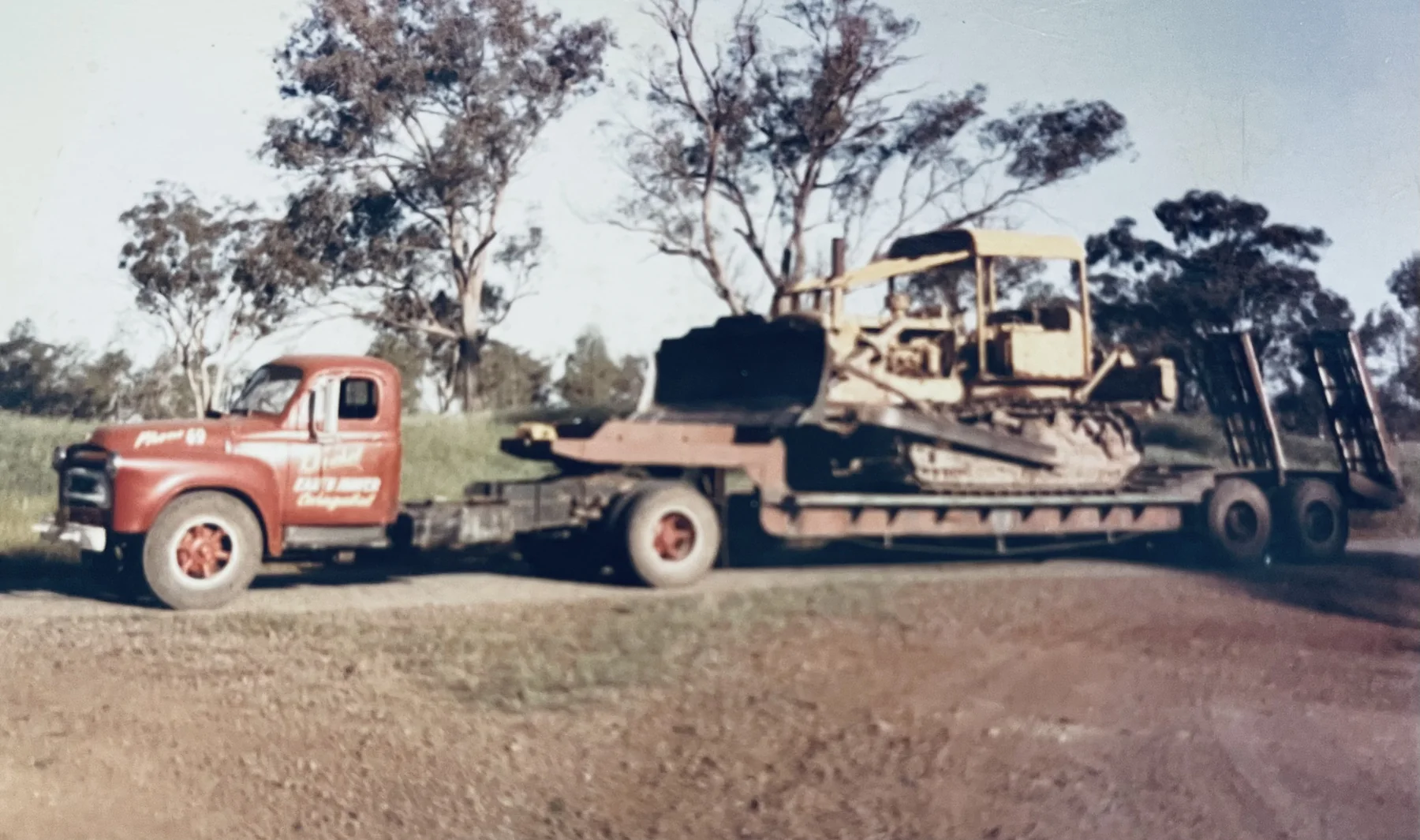 Early Huckel truck transporting tracked earthmoving machinery on a low-loader