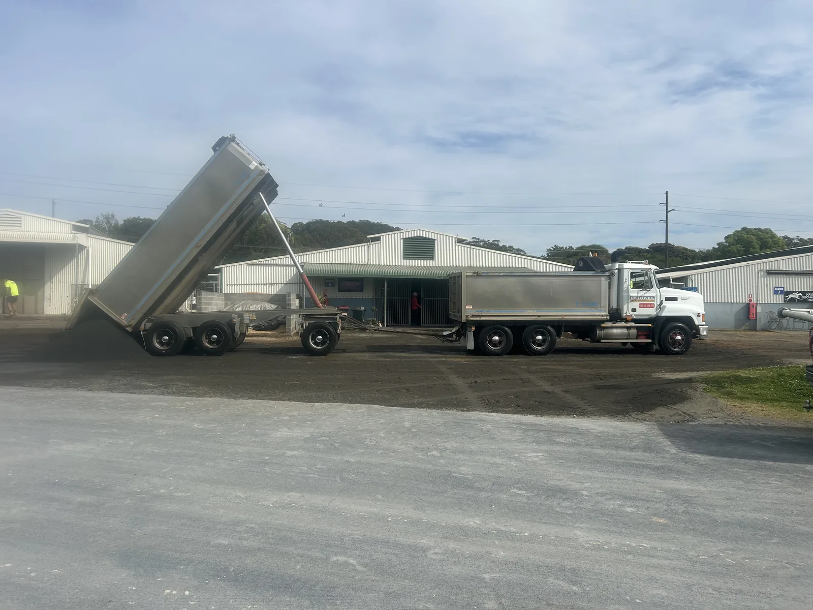 Truck and dog tipper delivering and placing material at an industrial site