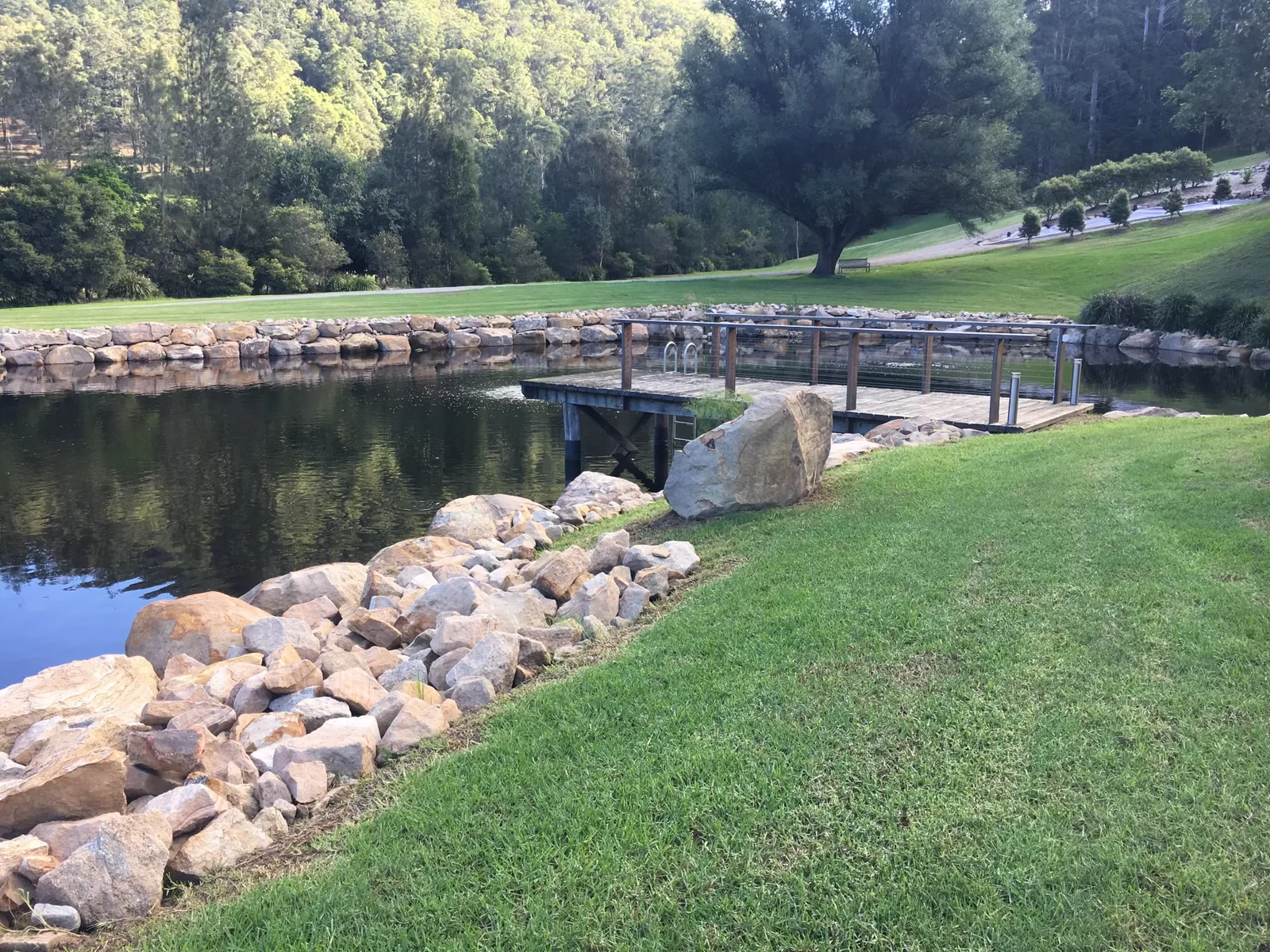 Completed landscaped water feature with sandstone edges and a timber bridge